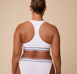 India showcases the racerback style from behind, highlighting the contoured shape and supportive fit of the Cloud Cotton Retro Racerback Bralette in White.