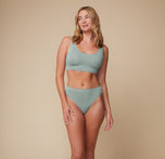Megan poses in a full body shot wearing the Cloud Cotton Scoop Bralette in Seaglass.