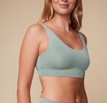 A close-up of Megan wearing the Cloud Cotton Scoop Bralette in seaglass, highlighting its smooth, wire-free design and everyday comfort, set against a beige background.