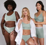 A group photo featuring Megan in the center wearing the Cloud Cotton Scoop Bralette and matching underwear in seaglass, Akesha on the left wearing the same set, and Anna on the right in the triangle bralette and cloud cotton logo boxer briefs. All models highlight the versatility and comfort of the Cloud Cotton Scoop Bralette in a neutral studio setting.