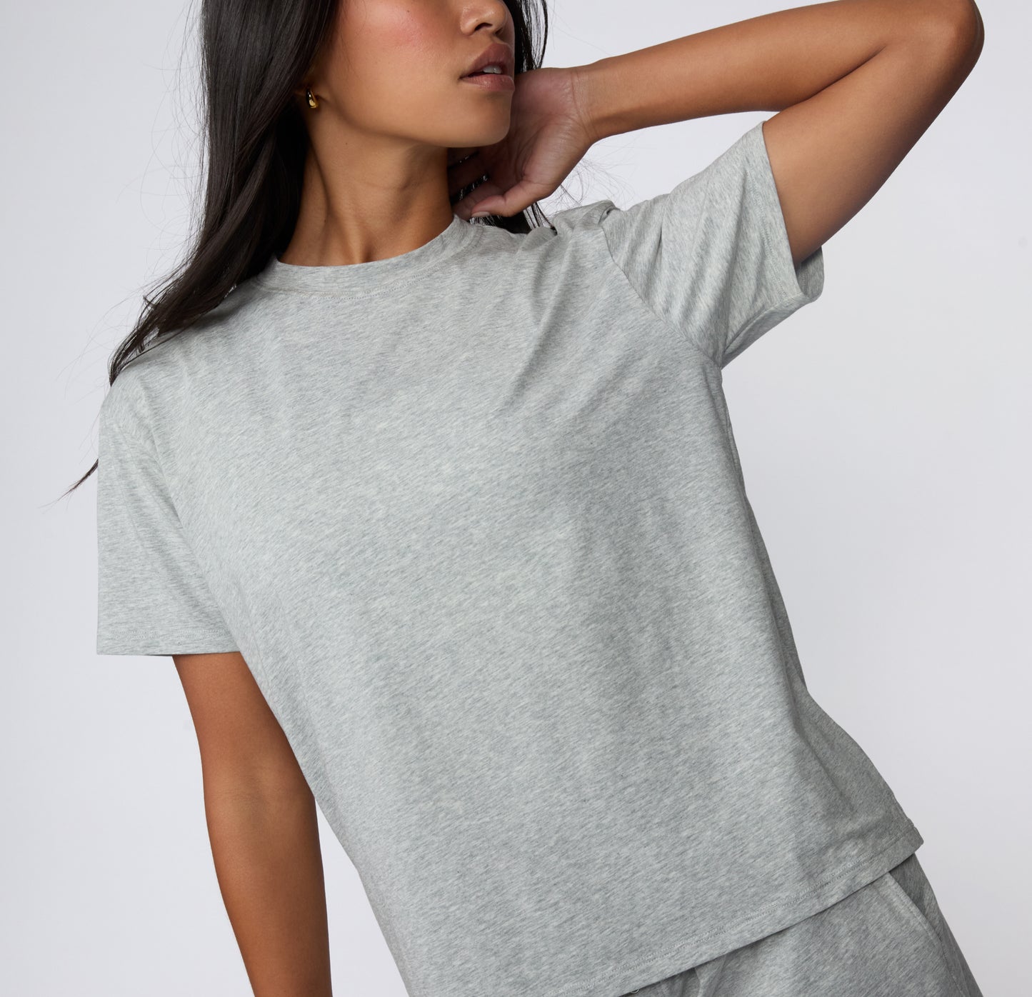 On a white studio backdrop, a close-up view of the Cloud Cotton Tee in Heather Grey highlights the crew neckline, short sleeves, and soft cotton modal fabric.