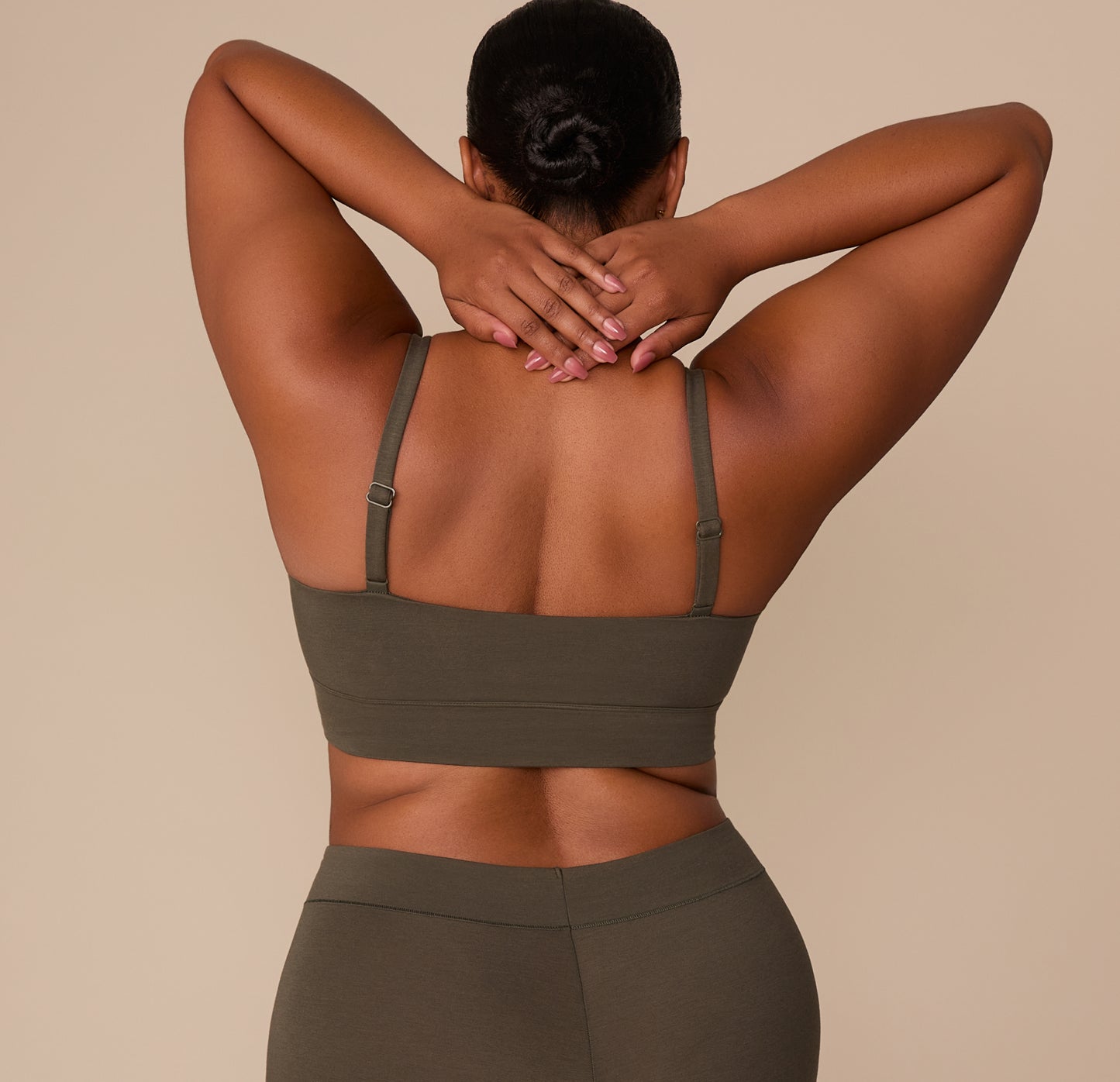 Back view of Zarria in the Cloud Cotton Thin Strap Bralette in Olive, arms raised to show the adjustable straps and longline band.
