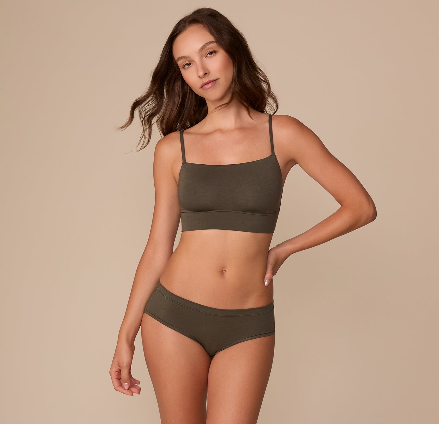 Full-body view of Alexis wearing the Cloud Cotton Thin Strap Bralette in Olive with the matching Hiphugger, standing in a relaxed pose.