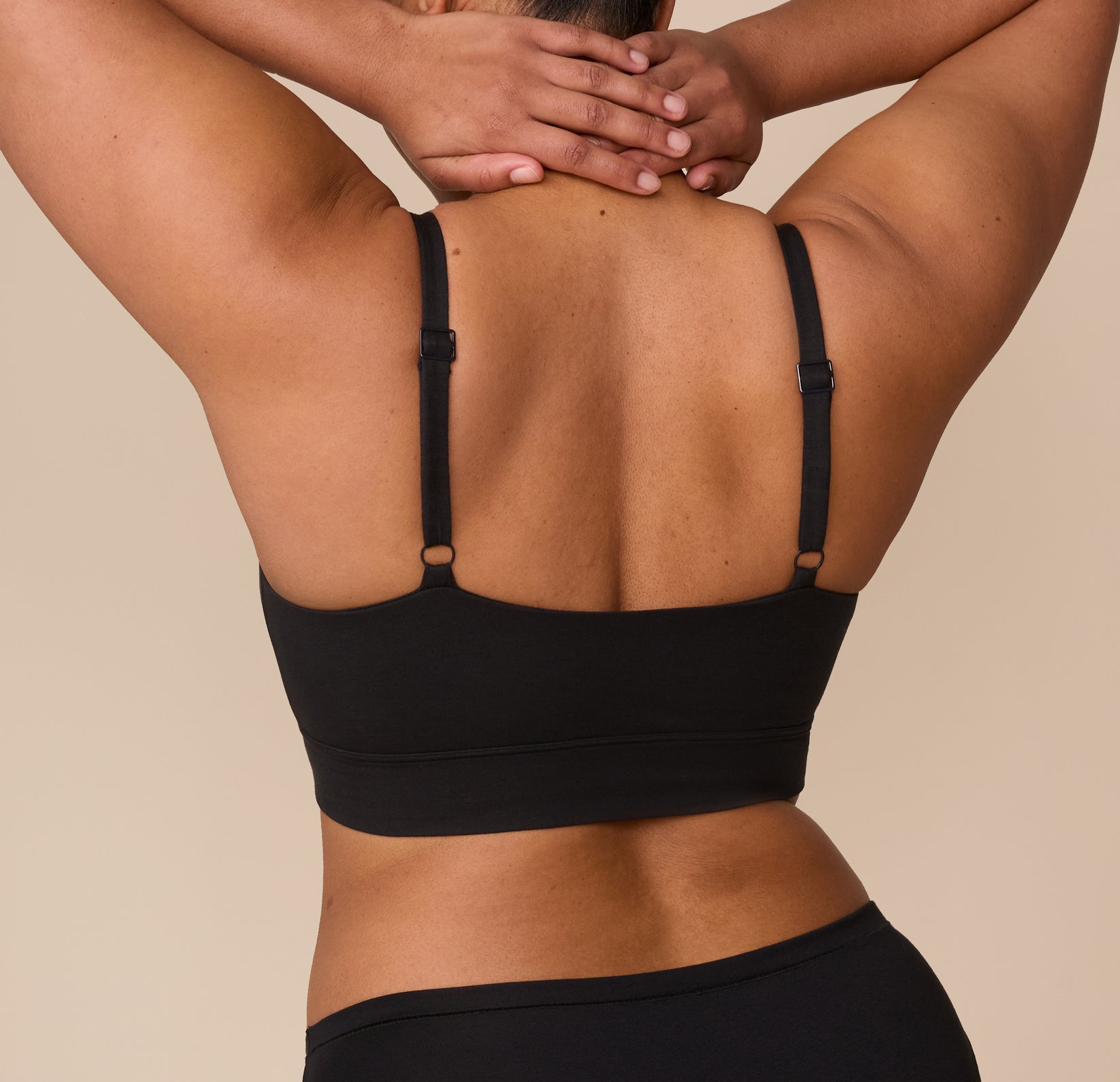 Back view of Zarria wearing the Cloud Cotton Thin Strap Bralette in Black, showing the wide back band and adjustable thin straps for a custom fit.
