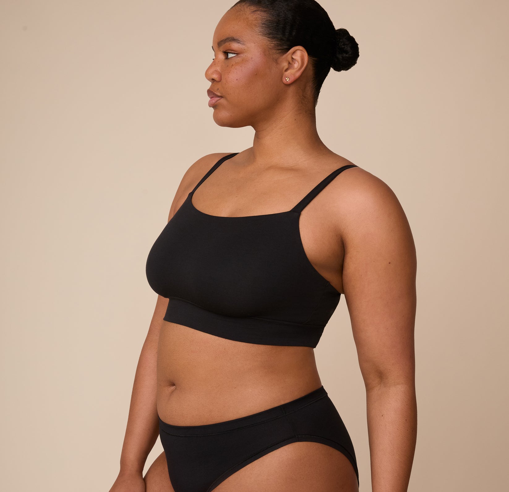 Side view of Zarria in the Cloud Cotton Thin Strap Bralette in Black, highlighting the bralette’s soft, minimal seam construction and low-profile design.