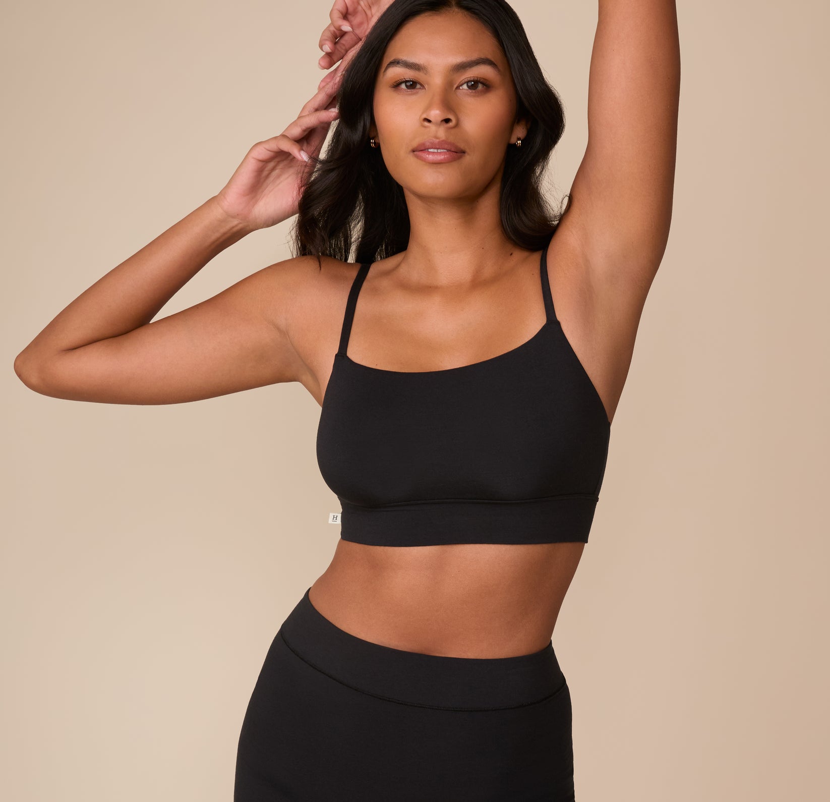 Victoria wears the Cloud Cotton Thin Strap Bralette in Black, standing with arms raised to showcase the fit and flexibility of the soft, breathable fabric. sizing: Victoria wears size Medium