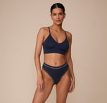 Full-body image of Marcela wearing the Cloud Cotton Highwaist Thong and matching Cloud Cotton Triangle Bralette in Midnight. Her relaxed stance highlights the coordinated comfort and clean silhouette.