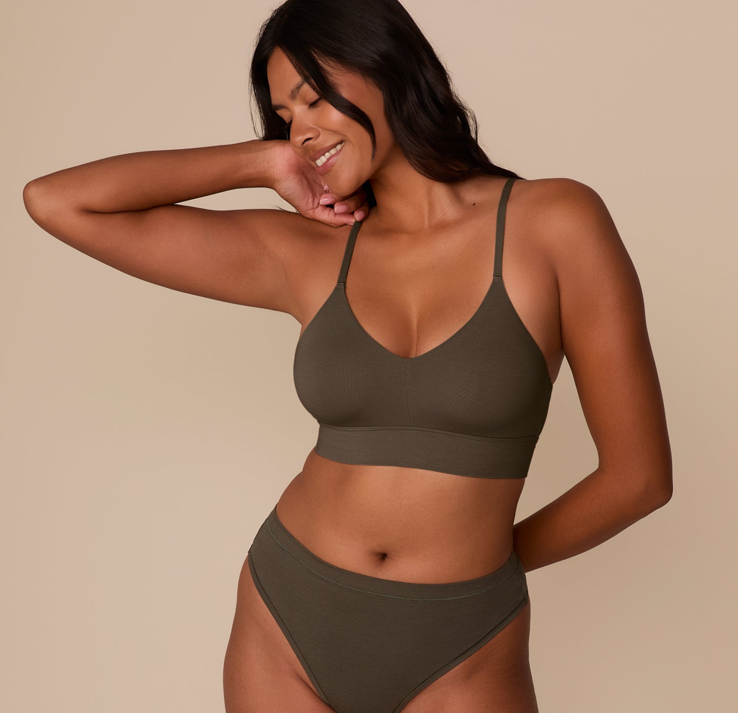 Victoria wearing the Cloud Cotton Triangle Bralette in Olive with matching Cloud Cotton Highwaist Thong. The bralette’s deep V neckline and longline band are visible. sizing: Victoria wears size Medium