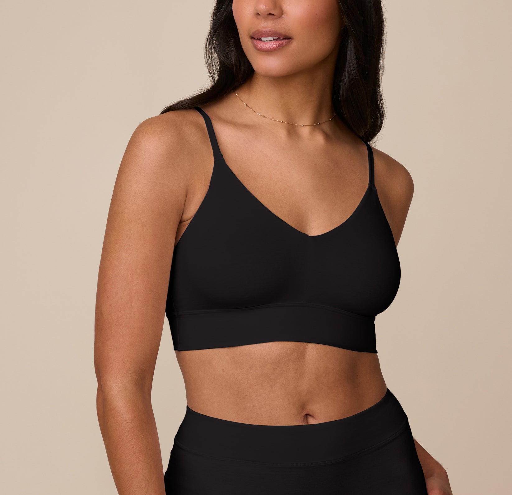 Nemesis wearing the Cloud Cotton Triangle Bralette in Black, shown from the front. The triangle silhouette features a deep V-neckline with thin adjustable straps and a wide underband for support. sizing: Nemesis wears size Medium