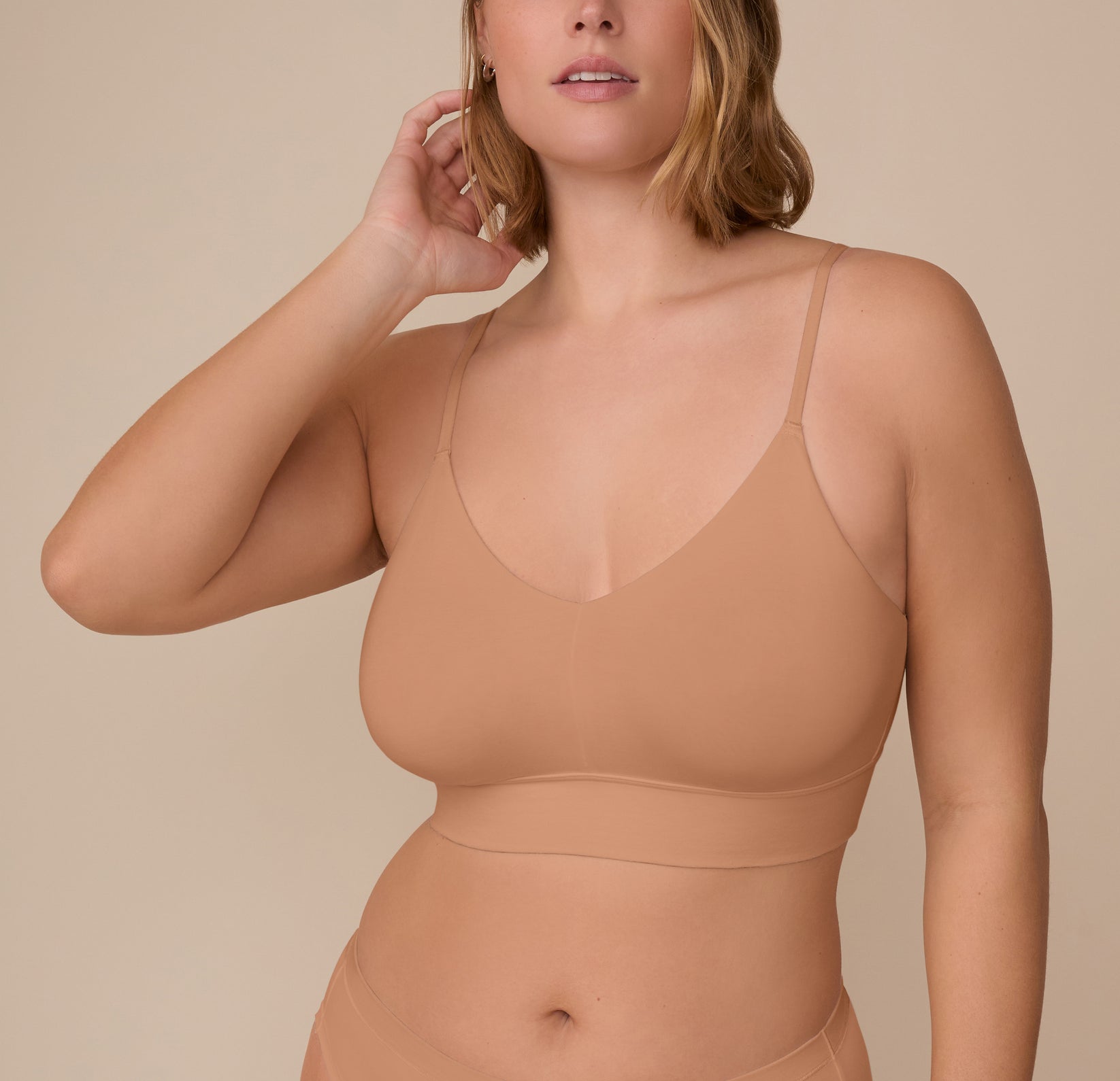 Sonnie wearing the Cloud Cotton Triangle Bralette in Dune, shown from the front. The triangle silhouette features a deep V-neckline, thin adjustable straps, and a wide underband that offers light support. sizing: Sonnie wears size XL