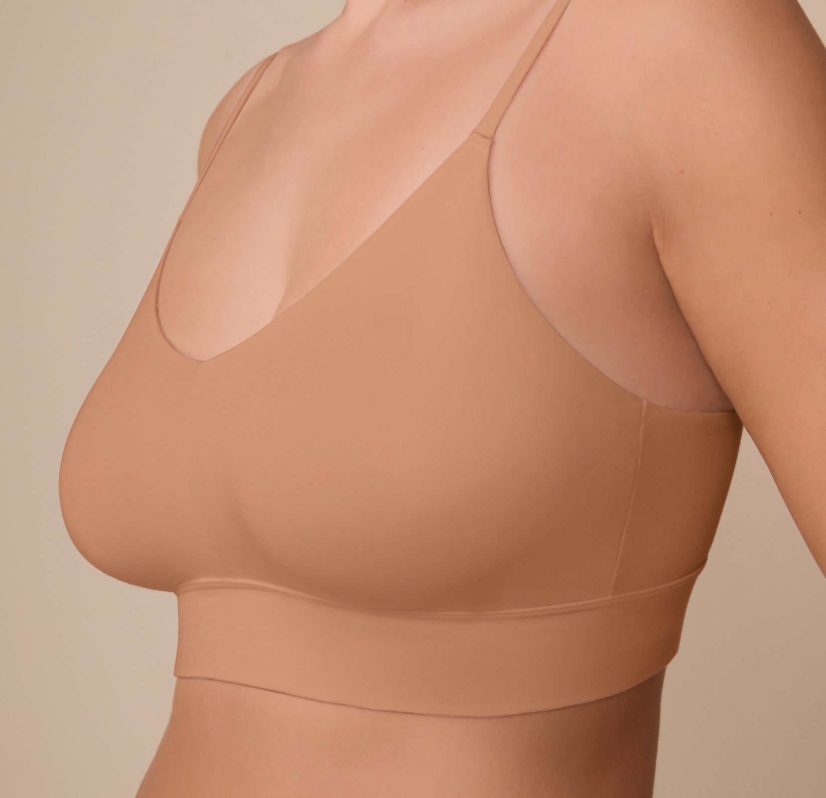 Close-up of Sonnie wearing the Cloud Cotton Triangle Bralette in Dune. The image captures the plunge neckline and smooth finish around the underband and sides.