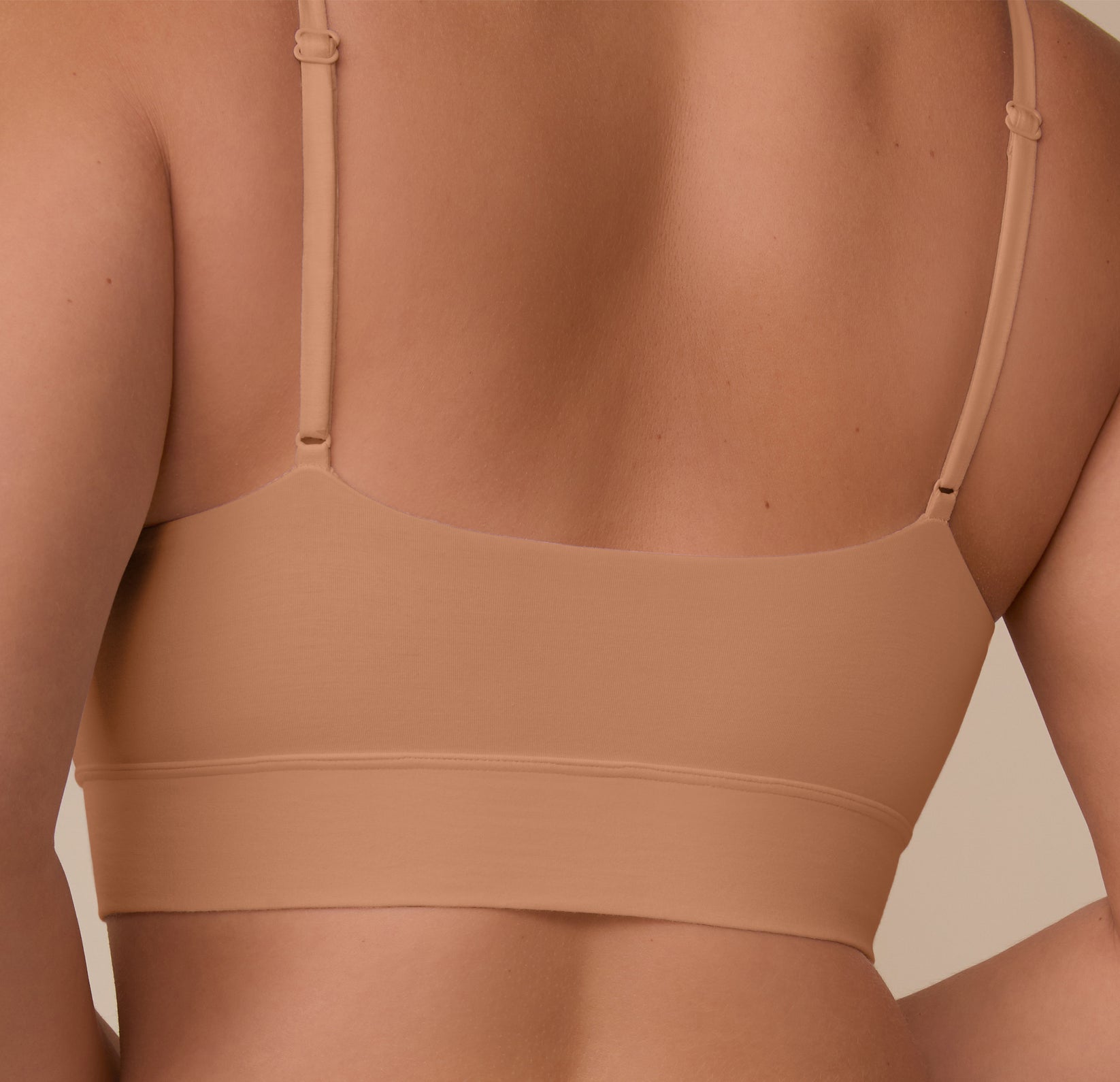 Back detail shot of Sonnie in the Cloud Cotton Triangle Bralette in Dune. The image shows the wide underband and slim straps that provide a custom-feel fit.