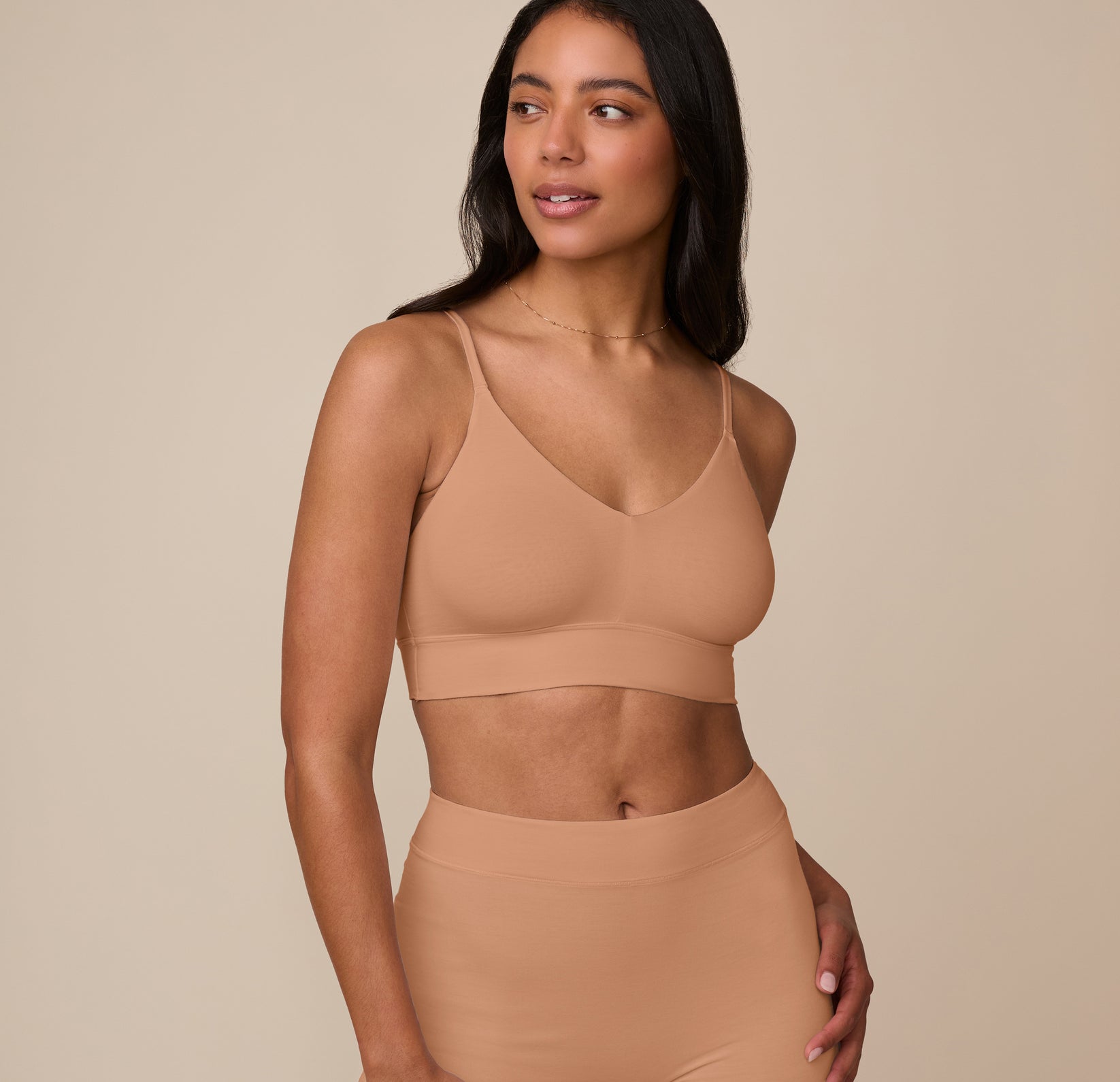 Nemesis wearing the Cloud Cotton Triangle Bralette in Dune, shown from the front. The minimalist cut and soft-touch fabric provide gentle shaping with no digging or pinching. sizing: Nemesis wears size Medium