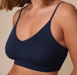 Up close view of Sonnie wearing the Cloud Cotton Triangle Bralette in Midnight. The low v-neck neckline and deep blue, cotton-modal fabric are emphasized.