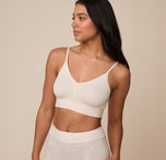 Three-quarter front view of model Nemesis in the Cloud Cotton Triangle Bralette in Quartz. The image captures the natural silhouette and light, but sturdy support offered by the bralette.