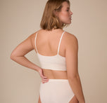 Back view of model Sonnie in the Cloud Cotton Triangle Bralette in Quartz. The image focuses on the supportive band and minimal stitching that enhance the bralette’s sleek look.