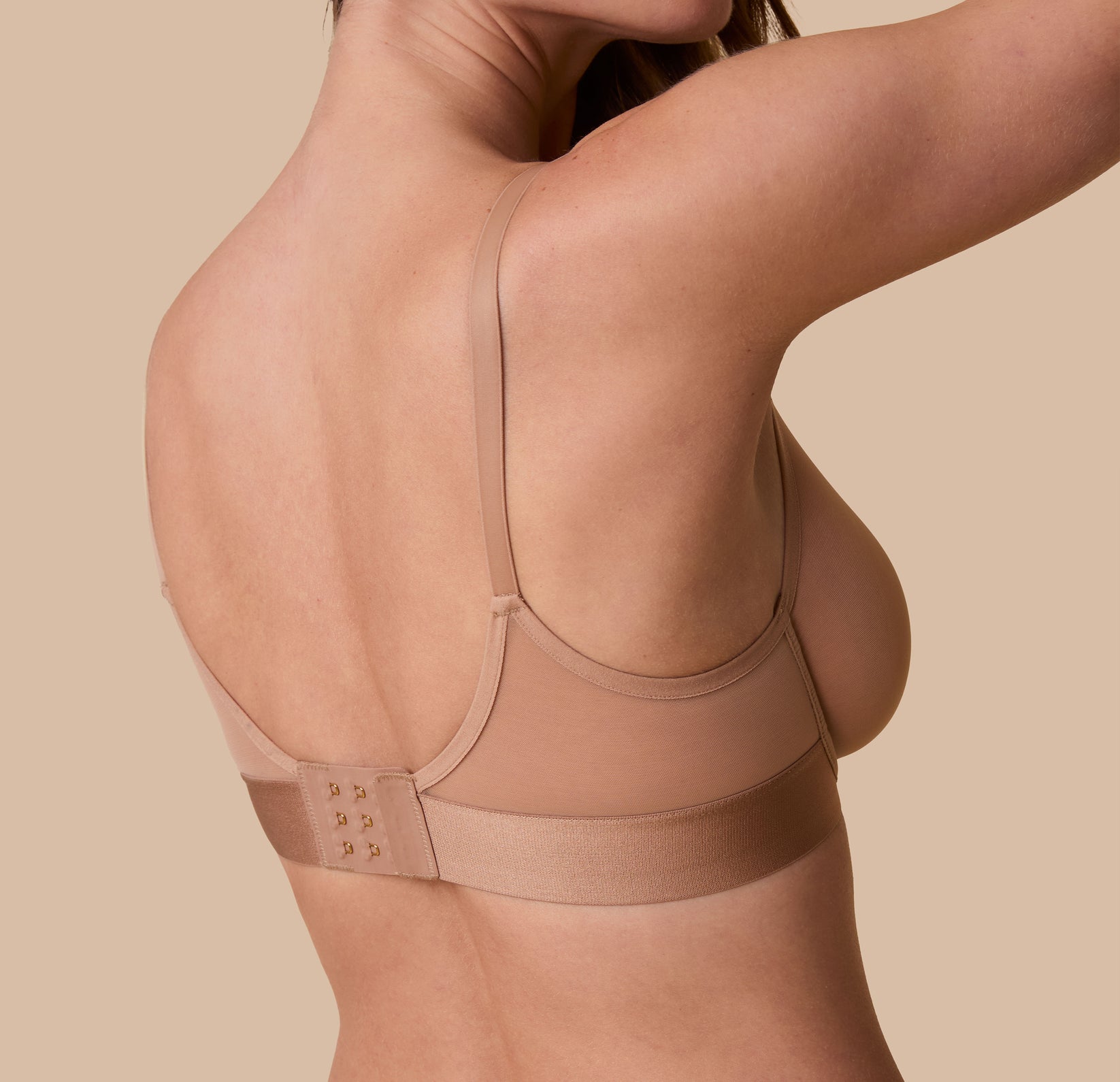 Back view of Gracie wearing the ComfortMesh Plunge Bra in Taupe, showcasing the supportive straps and wide back clasp.