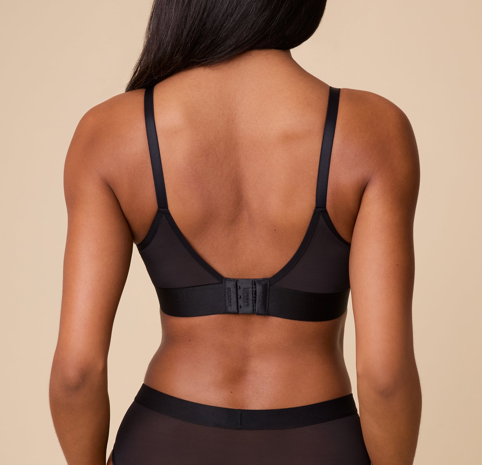 Back view of Ally showcasing the ComfortMesh Triangle Bralette in Black. The bralette has a low back design and a hook-and-eye closure for a comfortable fit.