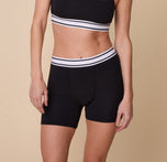 Close-up of Gracie wearing the Cloud Cotton Retro Boxer Brief in Black. The bottom of a matching bralette can be seen, emphasizing the matching striped underband. sizing: Gracie wears size Small