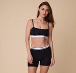 Full-body shot of Gracie wearing the Cloud Cotton Retro Boxer Brief in Black and matching Bandeau Bralette, standing in a relaxed pose against a neutral background.