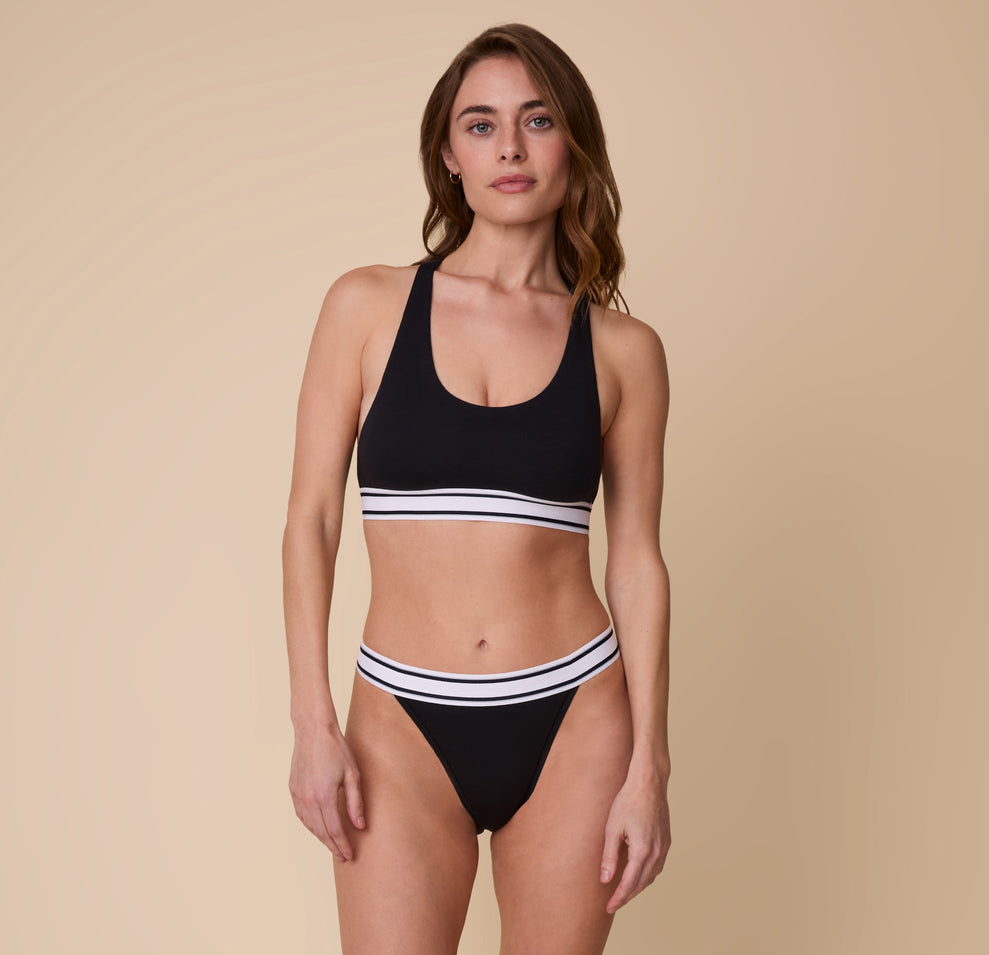 Full-body shot of Gracie in the Harper Wilde Cloud Cotton Retro French Cut Bikini in Black, showcasing the sporty yet comfortable fit of the set.