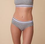 Close-up of Gracie wearing the Cloud Cotton Retro Hiphugger in Heather Charcoal. The soft fabric sits comfortably on her hips, with a wide elastic waistband featuring contrast stripes for a sporty look. sizing: Gracie wears size Small