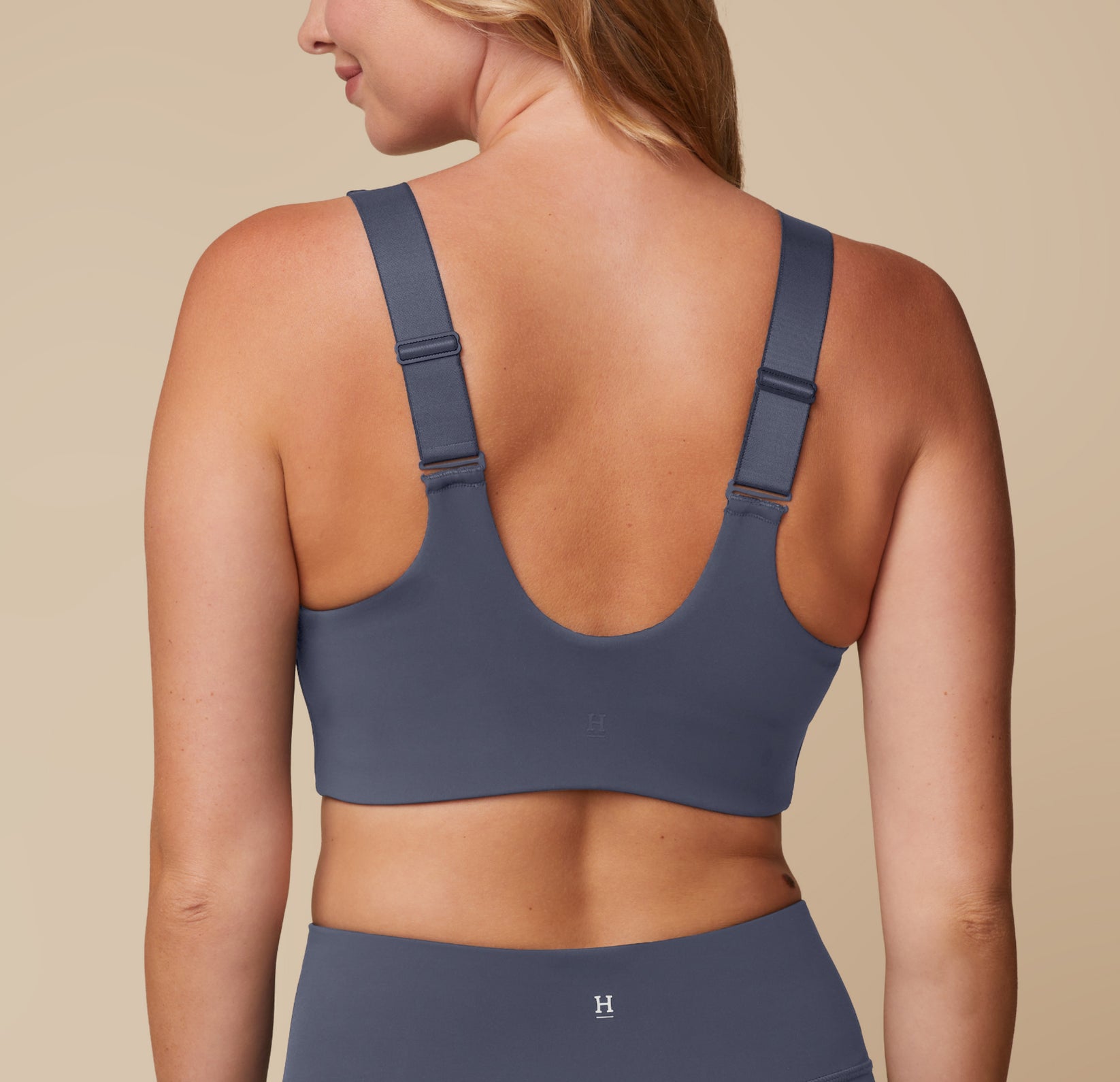 Back view of Megan wearing the Flex Convertible Sports Bra and Flex High Rise Legging in Slate, turned to display the adjustable and convertible straps.