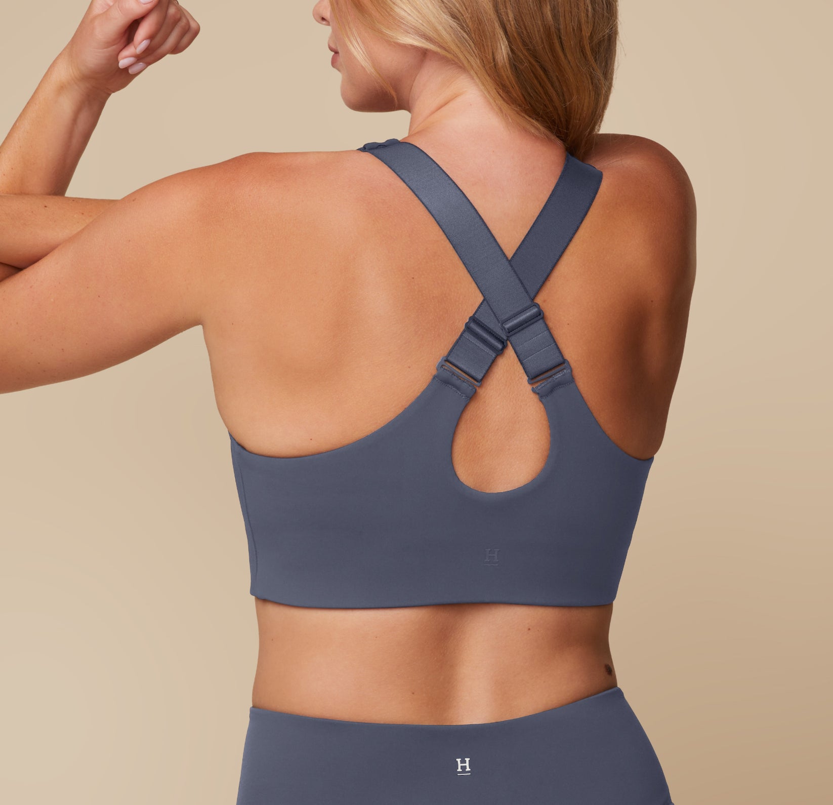Megan showing the back of the Flex Convertible Sports Bra in Slate, with the straps adjusted to cross in the back.
