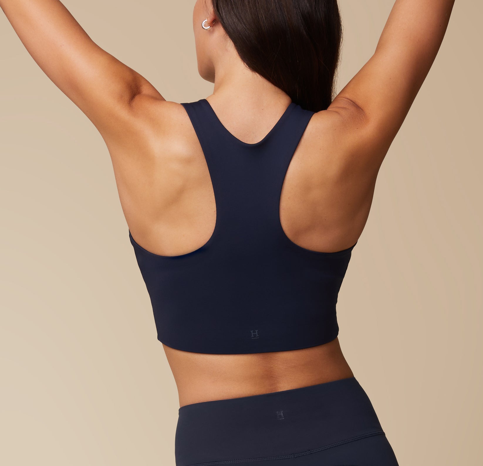 Anna in the Flex Racerback Sport Tank and Flex High Rise Leggings in Ink, with arms stretched above her head, showcasing the back of the racerback tank.