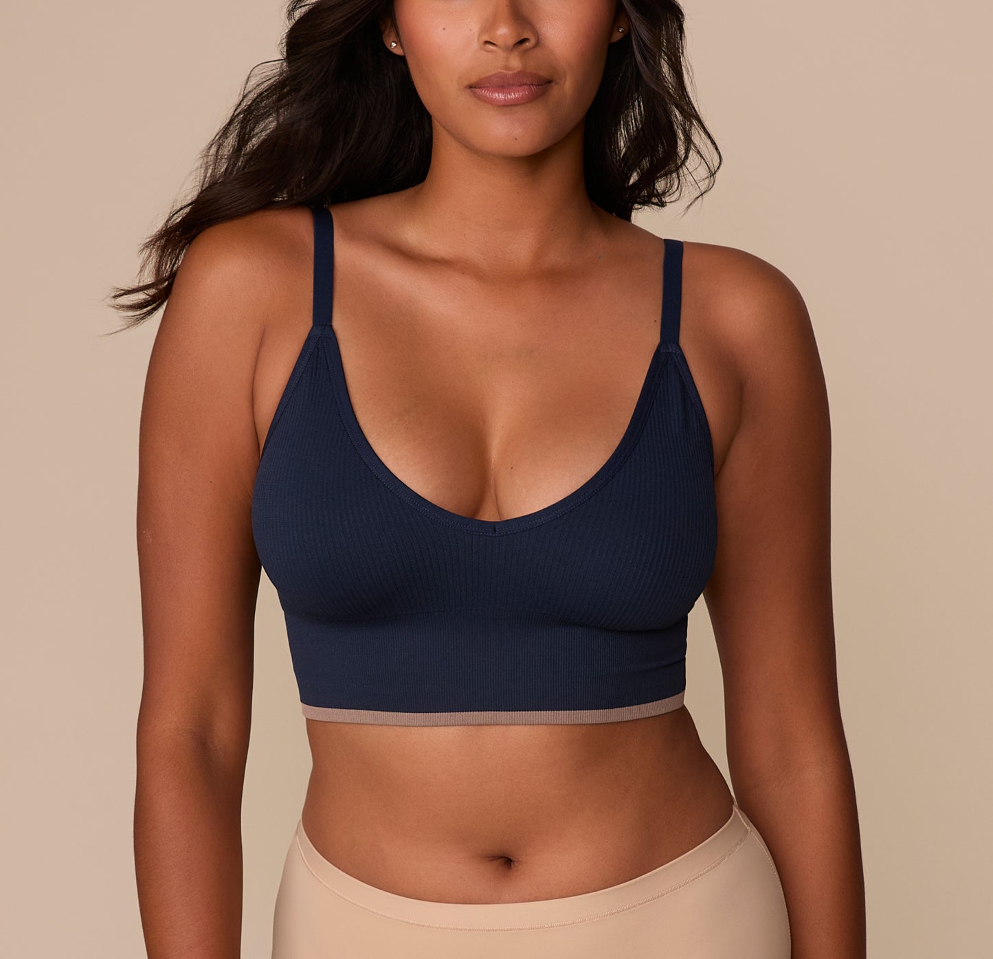 ront View
Victoria wearing the Lounge Rib Triangle Bralette in True Blue, shown from the front. The deep V neckline and thin adjustable straps enhance the natural shape, while the ribbed fabric adds texture and softness. The contrast taupe band at the bottom provides a subtle yet stylish finish. sizing: Victoria wears size Medium