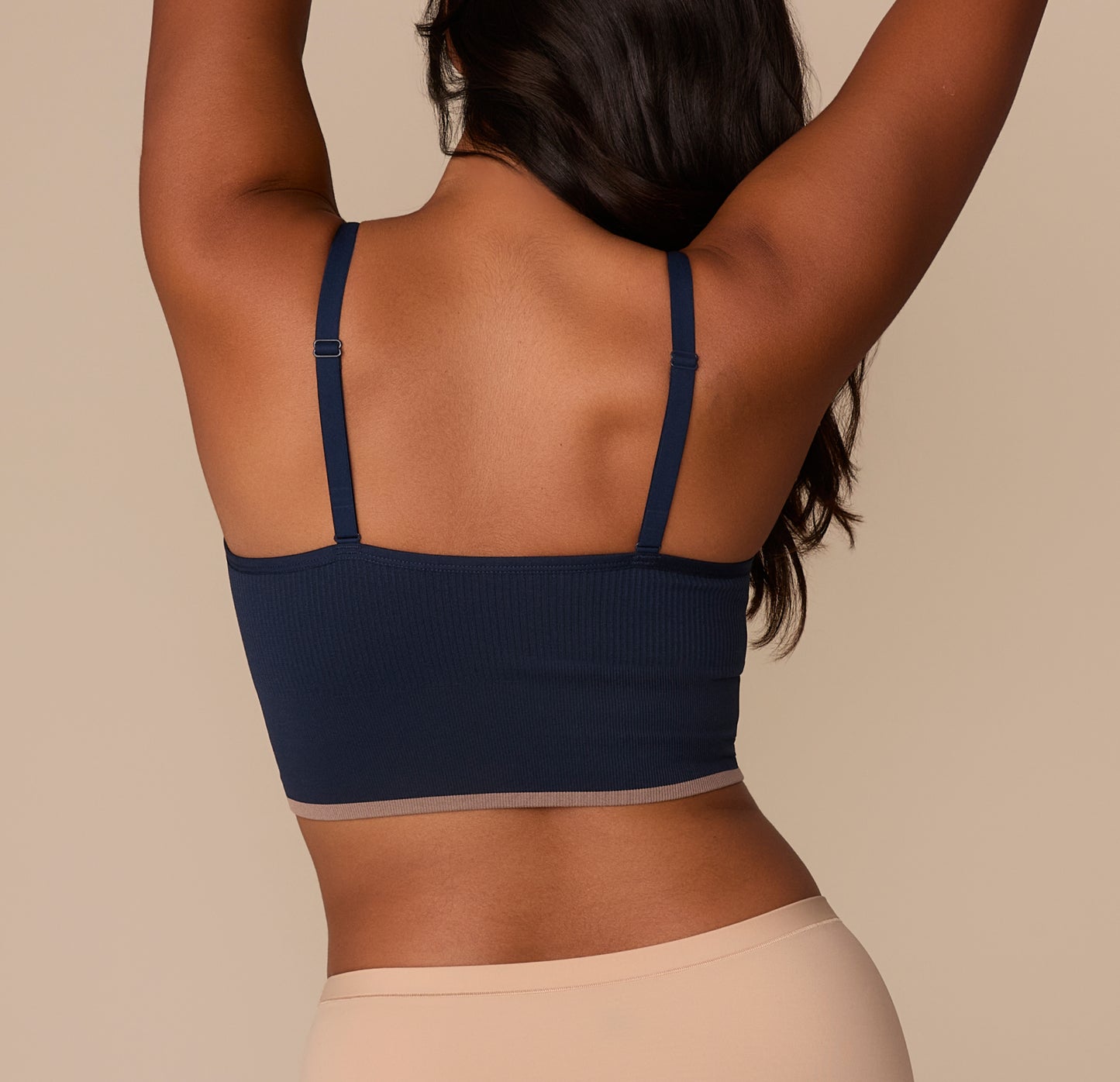 Rear view of Victoria in the Lounge Rib Triangle Bralette in True Blue. The slim adjustable straps connect to a straight-cut back panel, allowing for a secure and comfortable fit across the shoulders. The ribbed texture and contrast hem detail continue around the back.