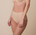 A side view of Gracie wearing the No-Show Highwaist Brief in Beige, emphasizing its high-rise waistband and smoothing effect.