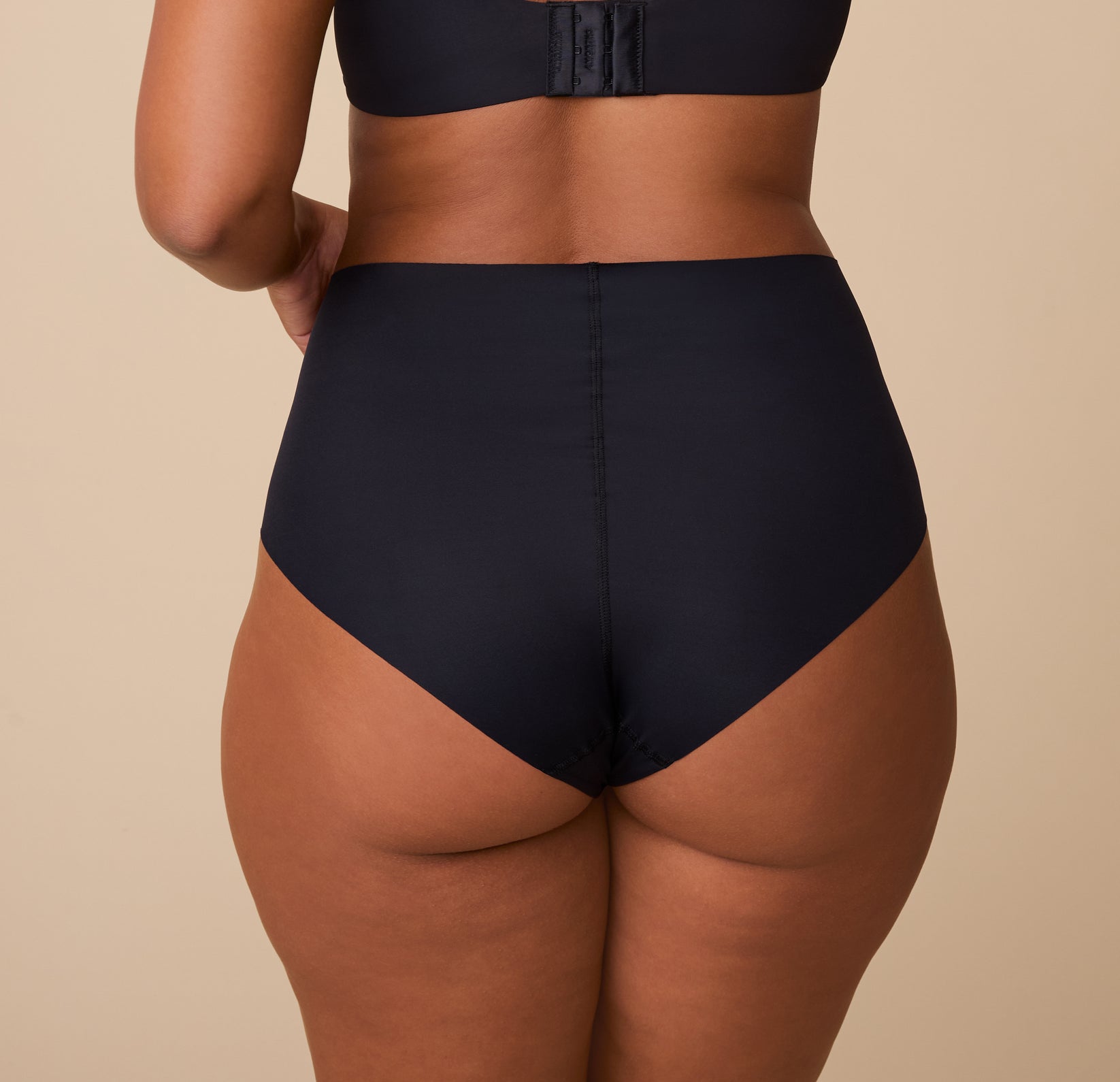 India is shown from behind, highlighting the full-coverage back and raw-cut edges for a sleek, no-show finish.