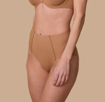 A three quarter profile of Gracie in the No-Show Highwaist Brief in Tan, emphasizing the soft, seamless waistband and smoothing fabric.