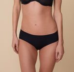A close-up of Gracie wearing the No-Show Hiphugger in Black. The seamless, mid-rise design sits smoothly against her body, creating a sleek and invisible look under clothing. sizing: Gracie wears size Small