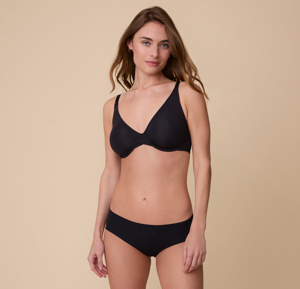 Gracie poses in the No-Show Hiphugger in Black paired with a matching Base Unlined Bra. The lightweight, no-show fabric sits effortlessly on her skin.