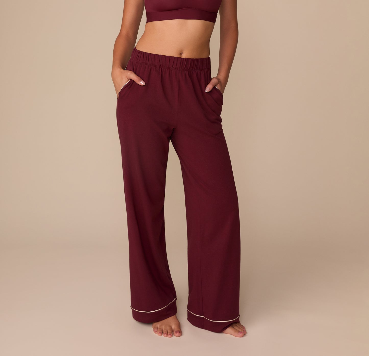 Front view of model Alexis wearing the Perfect Pima Pajama Pants in Bordeaux. The pants have a relaxed, wide-leg silhouette with contrast piping at the hem and an elastic waistband. sizing: Alexis wears size Small