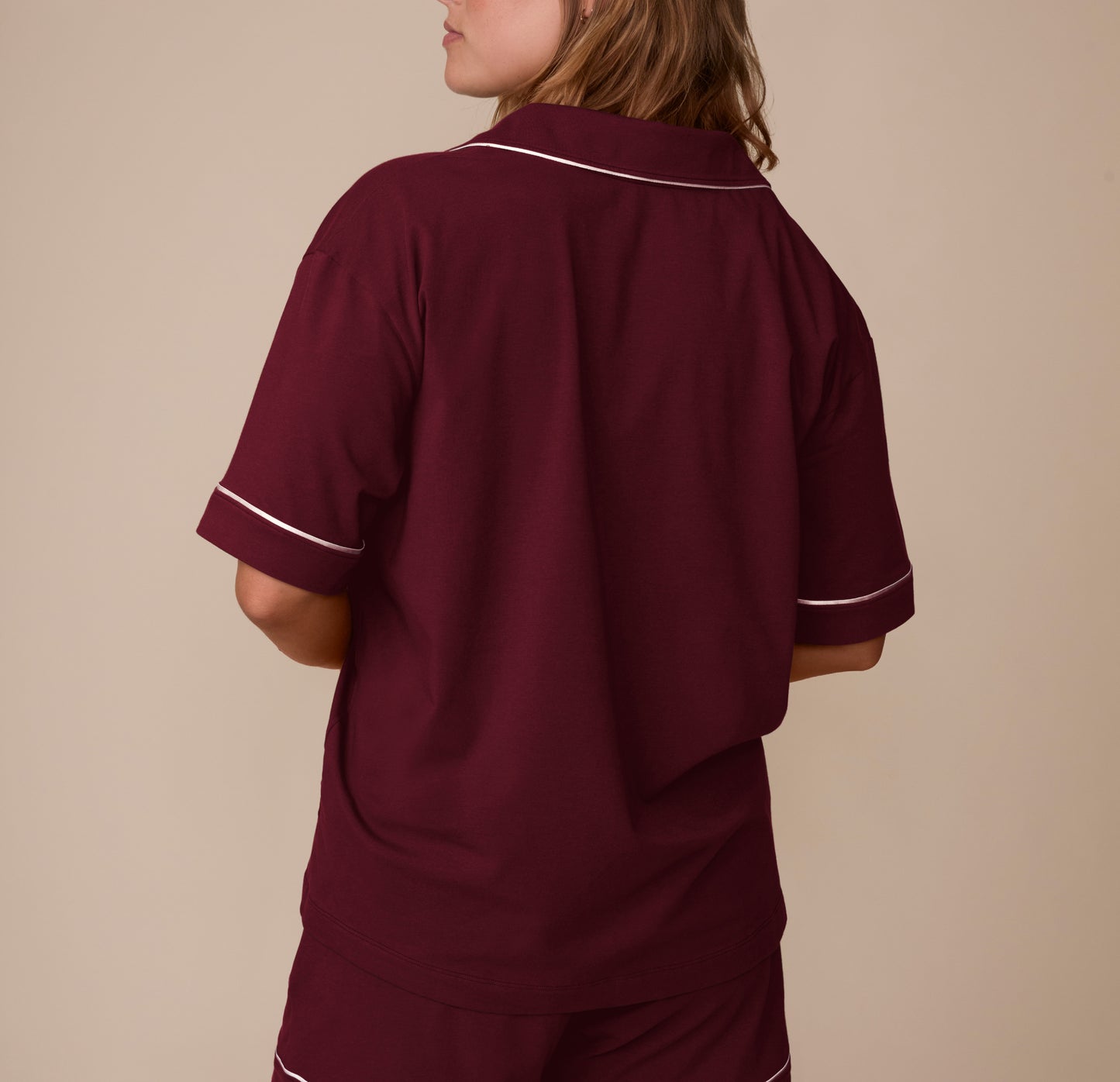 Back view of model Sonnie in the Perfect Pima Pajama Shirt and Shorts in Bordeaux. The image highlights the relaxed fit and smooth drape of the lightweight fabric.