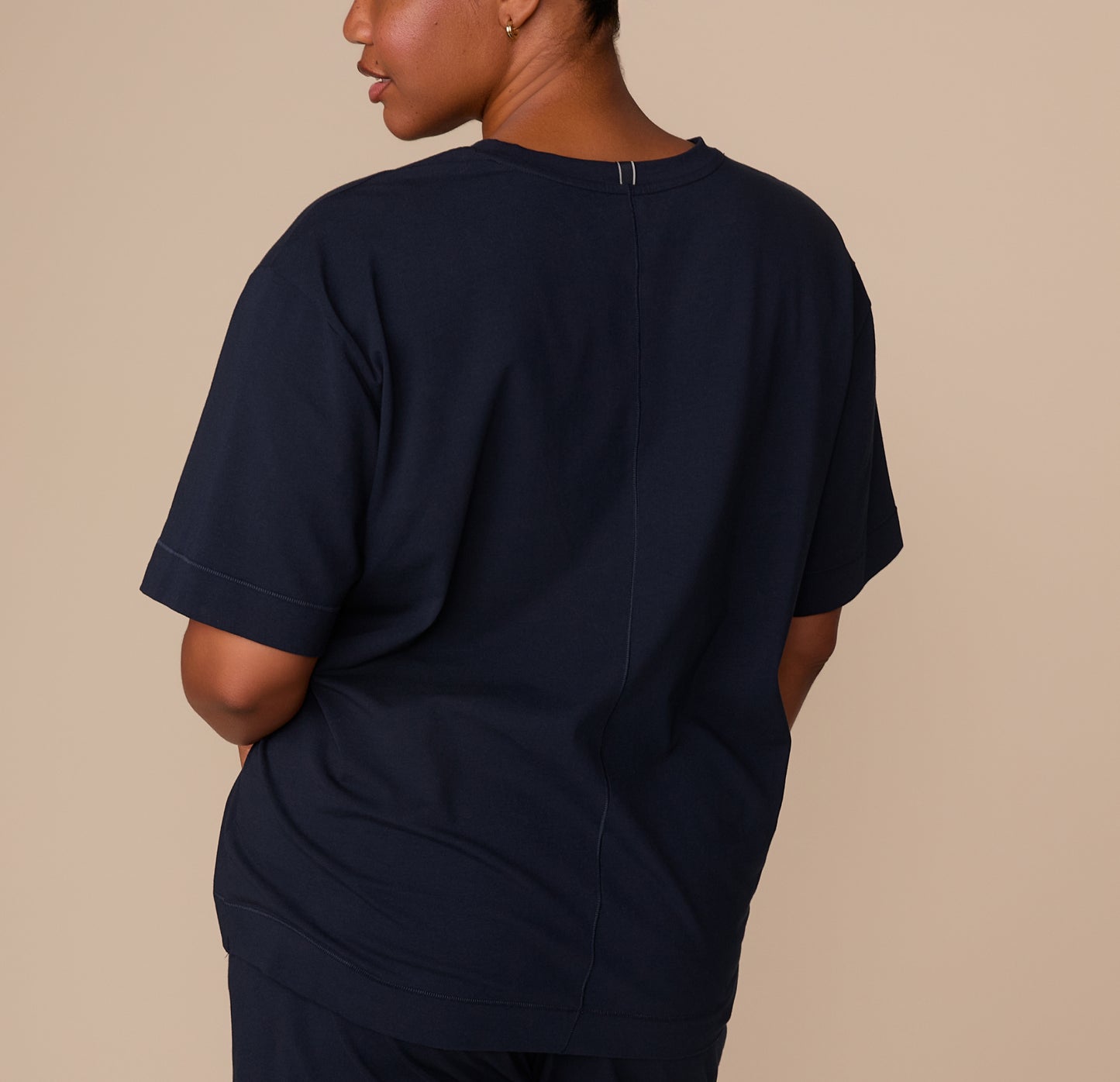 Rear shot of Zarria in the navy pajama tee shows the straight hem and center back seam, highlighting the tee’s relaxed silhouette and soft drape.
