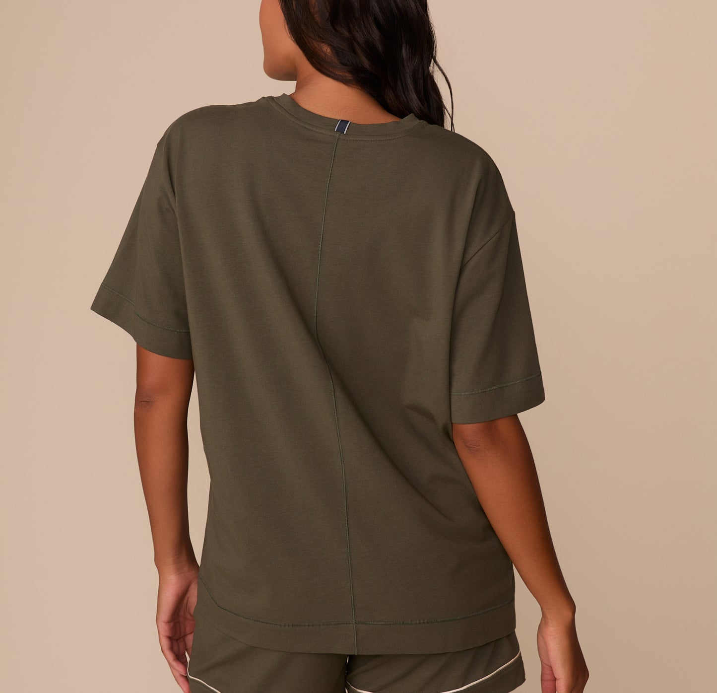 Back view of Victoria in the Perfect Pima Pajama Tee in Olive. The tee features a center back seam and a tag at the neckline.
