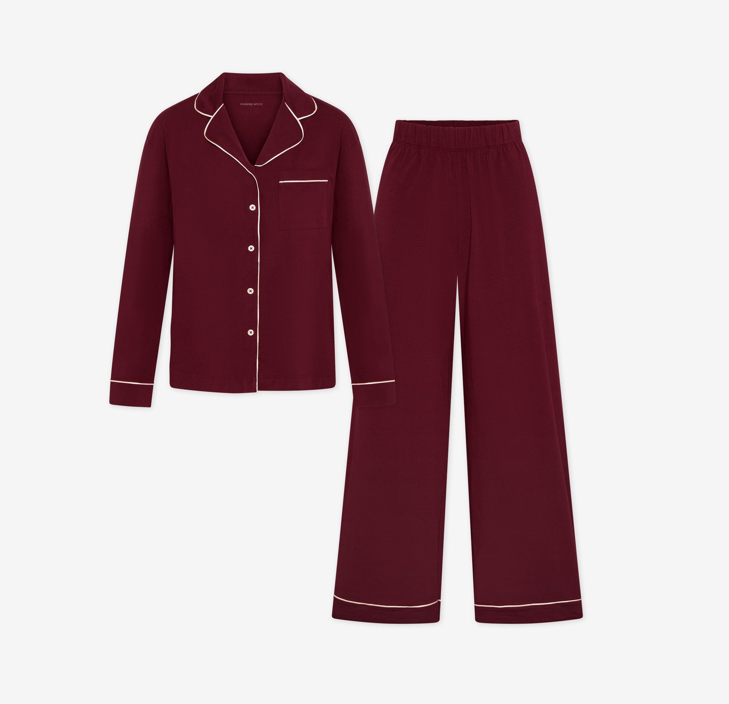 Harper Wilde Pima Pajama Set in Bordeaux. Includes long sleeve, button-up top with white piping and matching long pajama pants. Set laid flat on a white background.