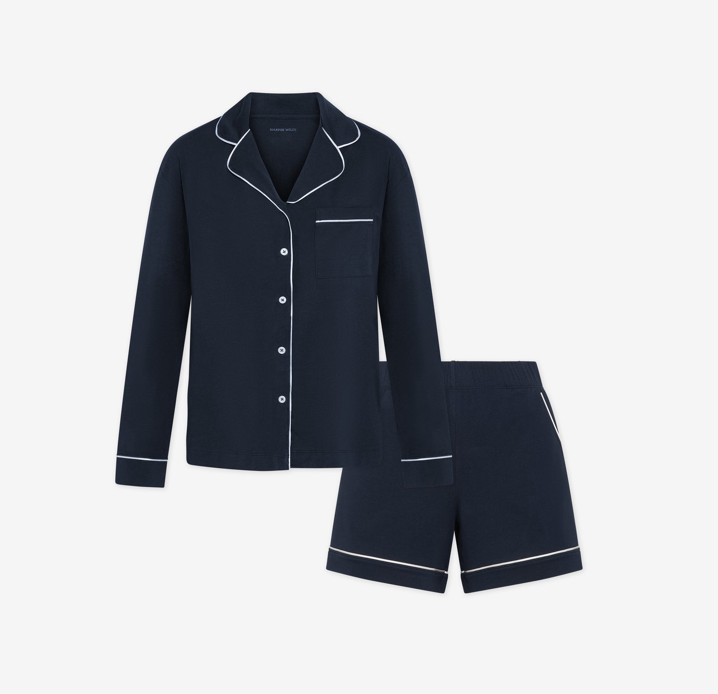 Harper Wilde Pima Pajama Set in Navy. Includes long sleeve, button-up top with white piping and matching pajama shorts. Set laid flat on a white background.