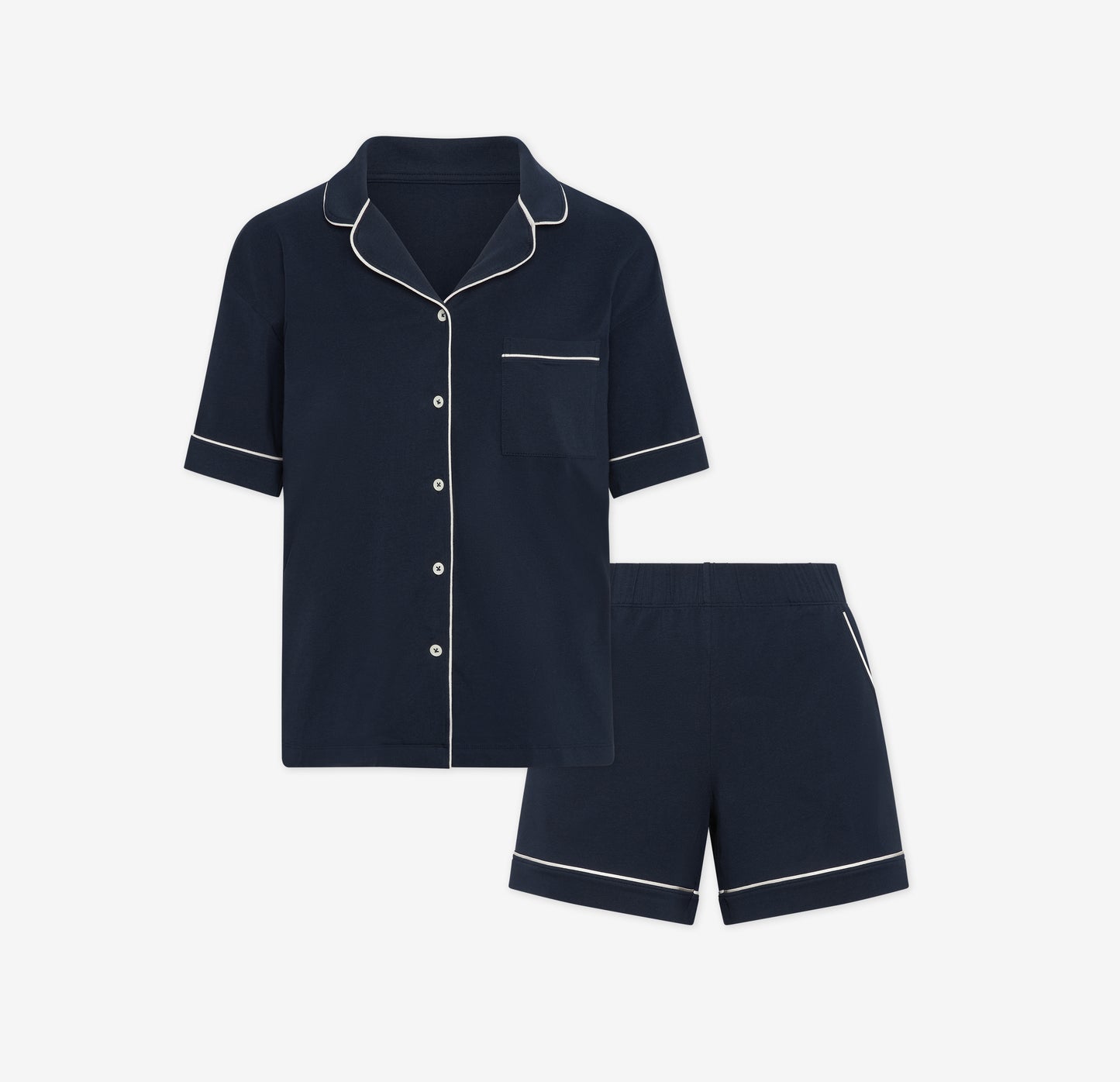 Harper Wilde Pima Pajama Set in Navy. Includes short sleeve, button-up top with white piping and matching pajama shorts. Set laid flat on a white background.