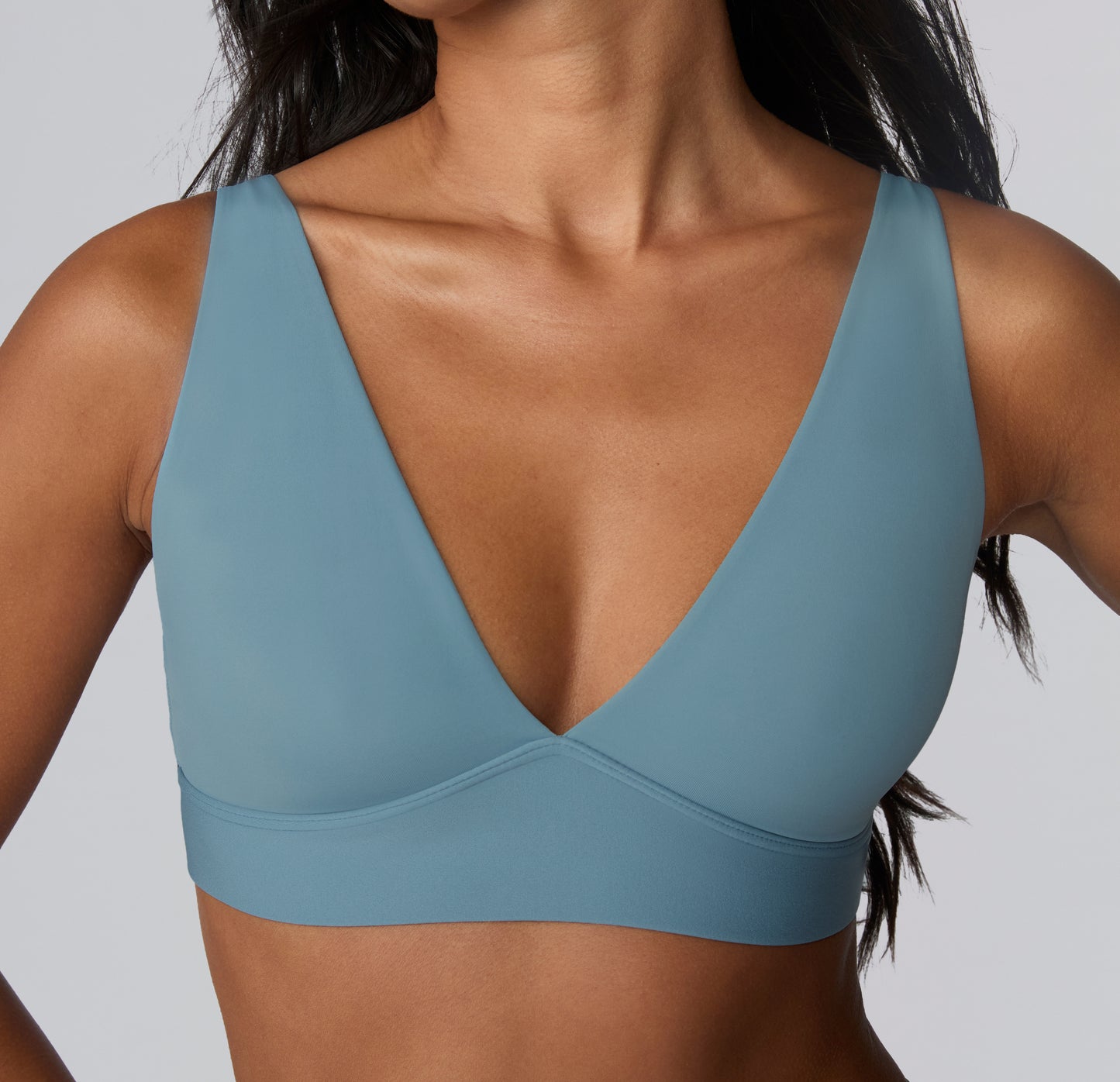 On a light studio backdrop, a close-up front view shows Amber wearing the Bliss Adjustable Bralette in Poolside, highlighting the plunge neckline, smooth microfiber fabric, and wireless band designed for comfortable everyday support.