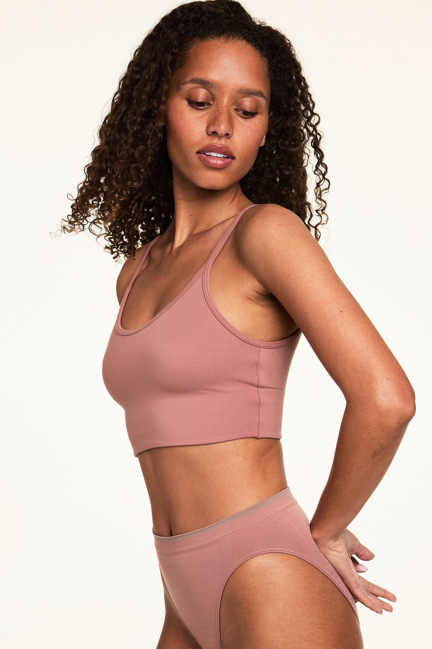 On a light studio backdrop, Courtney wears the Whipped Knit Scoop Bralette in Plum with matching underwear. The bralette features a scoop neckline, thin straps, and a smooth knit finish designed for everyday comfort.