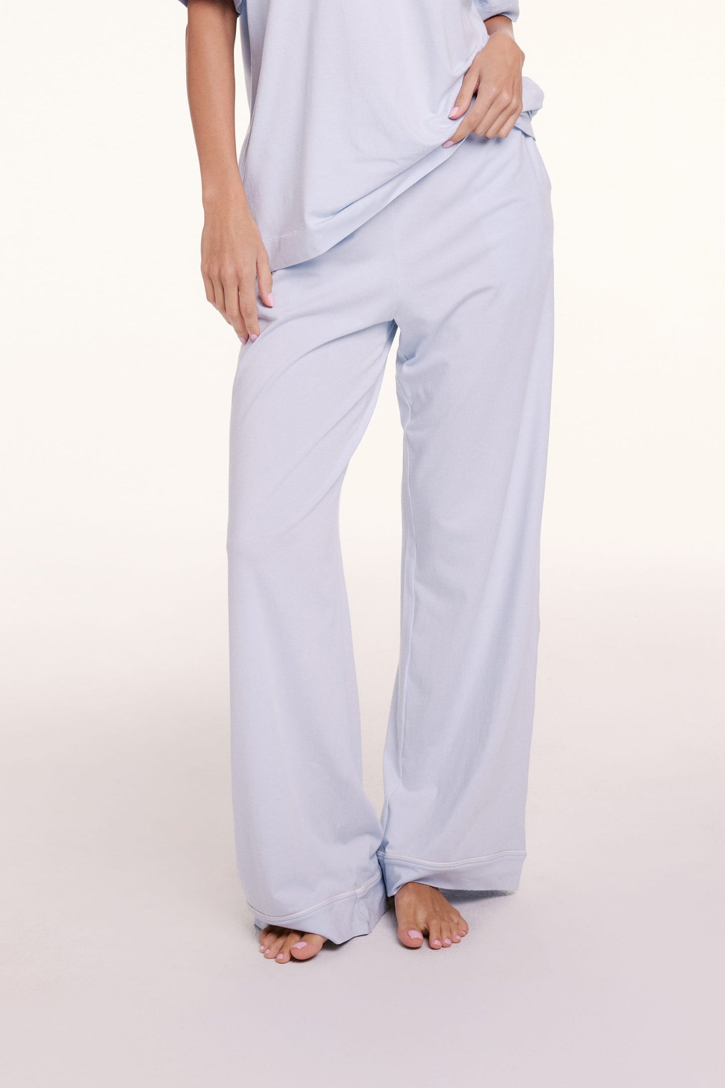 On a light studio backdrop, Linni wears the Perfect Pima Pajama Pants in Soft Blue, showing the relaxed fit through the leg and soft drape of the fabric.