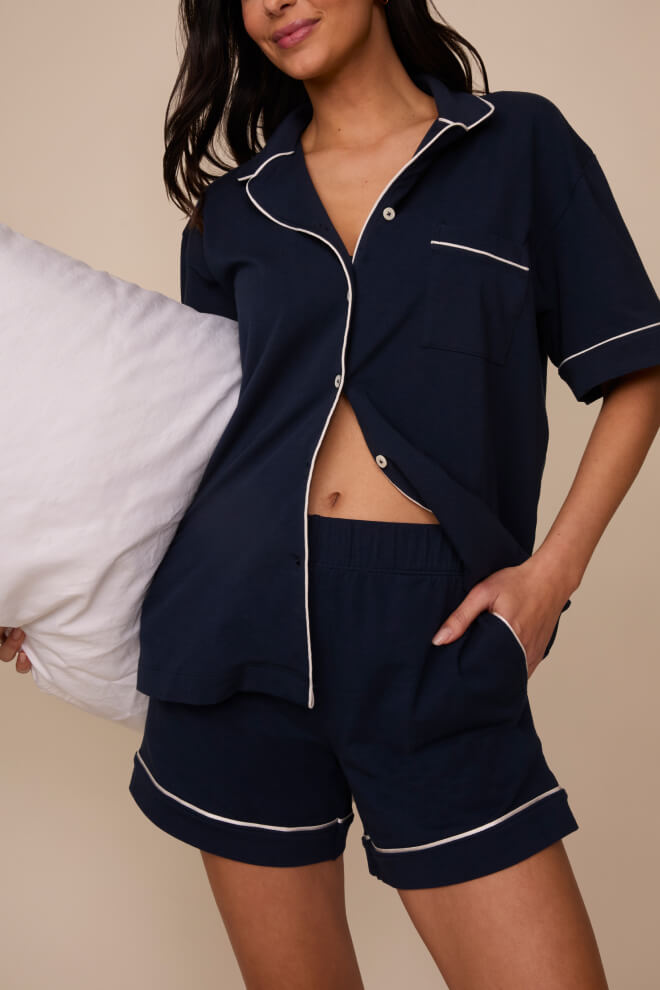 Model wearing Perfect Pima Shirt & Shorts set with white piping standing against a beige backdrop.