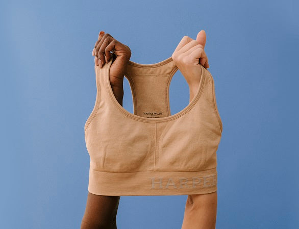 Two arms holding Sports Bra in Beige
