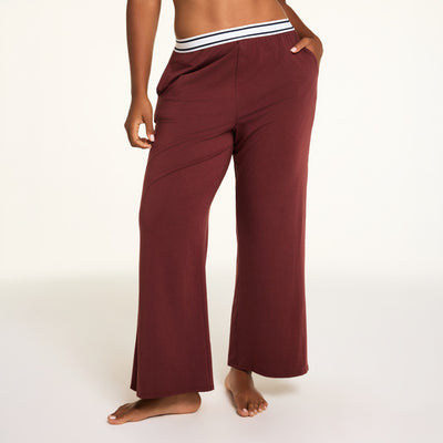 Hero close-up of the Cloud Cotton Pant in Cabernet, a relaxed straight-leg lounge pant in cloud-soft cotton-modal fabric with an elastic waistband and side pockets, paired with the Cloud Cotton Long Sleeve T-Shirt in Cabernet.
