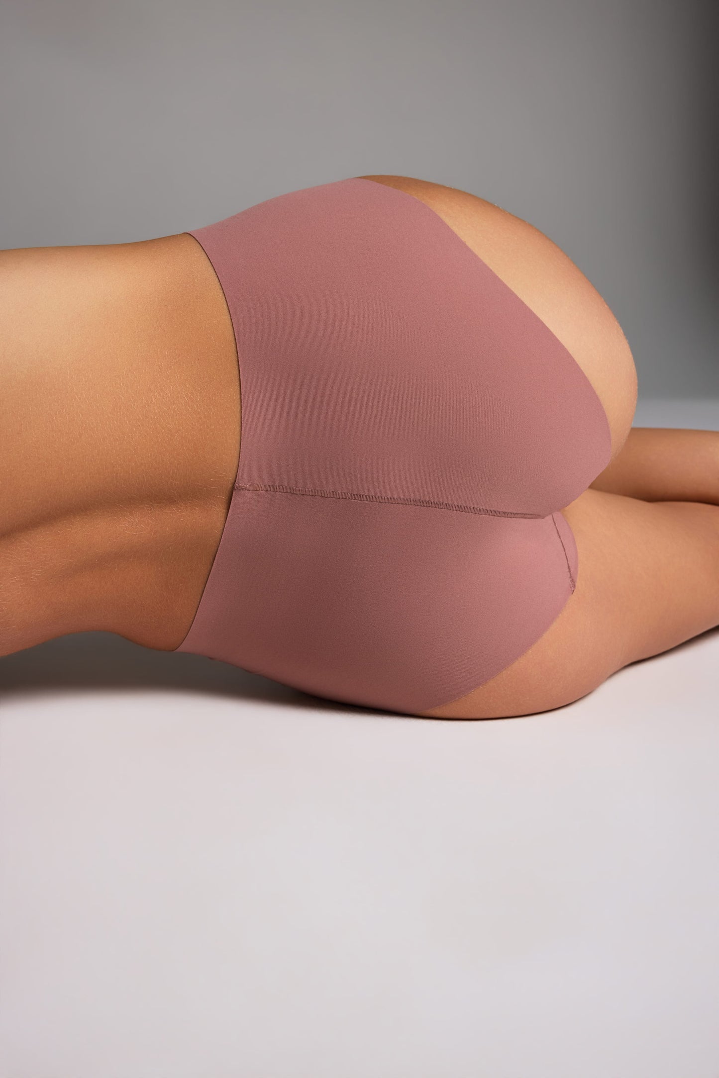 In a studio setting, Holly wears the Whipped Knit No-Show Highwaist Brief in Plum, shown in a close-up back view to highlight the high-waisted cut and smooth fabric. sizing: Holly wears size Small 
